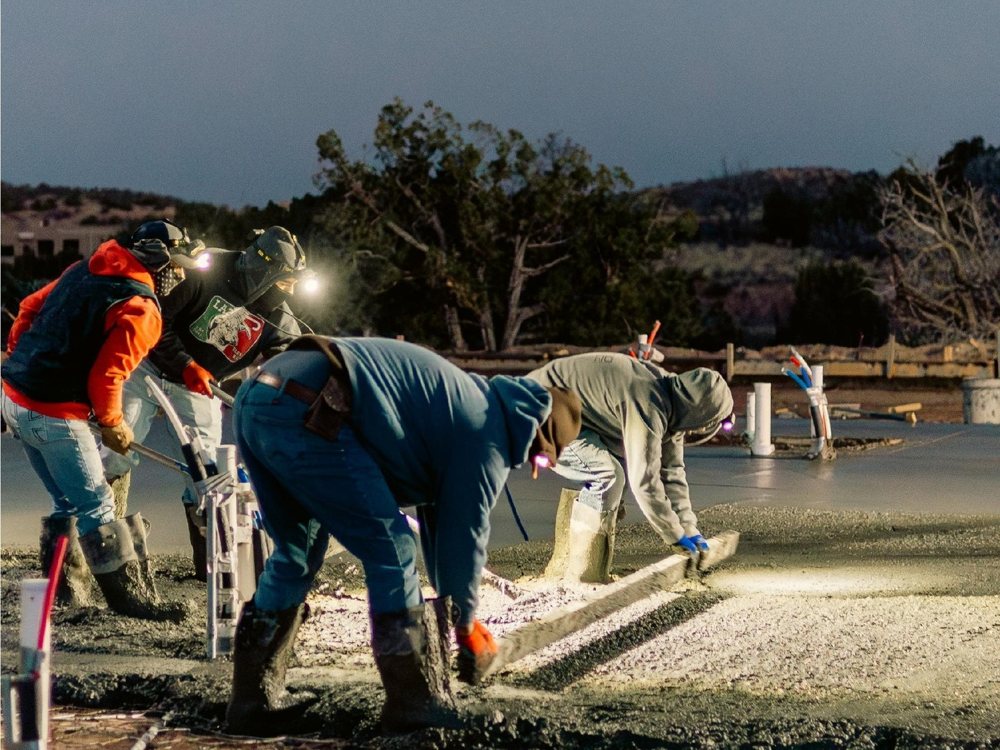 Solano Builders crew finishing a concrete foundation pour at dusk in New Mexico