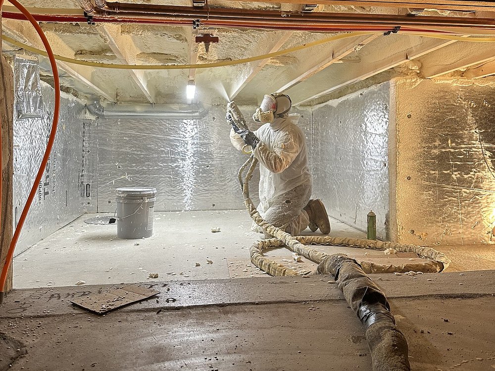 Solano Builders technician spraying foam insulation inside a framed home in New Mexico